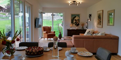 Hüttendorf - Frühstück: Brotservice - Enneberg - Essensbereich & Wohnzimmer mit Blick auf Garten und Bergwelt - Lodge Sirius  - TYROL PURElife Lodges 