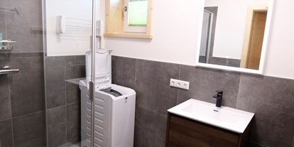 Hüttendorf - Schwerpunkt: Wanderurlaub - Oberaichwald - Badezimmer mit Dusche und Waschmaschine im Erdgeschoss - Designchalets Heidialm-Falkertsee