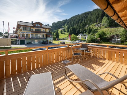 Hüttendorf - zustellbares Kinderbett - Irdning - Eigener Balkon mit Liegen und Sonnenschirm - Dorf-Chalets Filzmoos