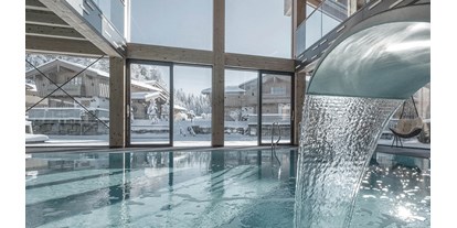 Hüttendorf - Pools: Innenpool - Österreich - INNs HOLZ Ausblick vom Indoorpool auf das Chaletdorf im Winter - INNs HOLZ Chaletdorf