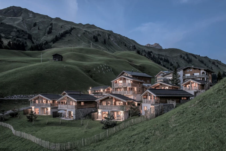 Holzchalets mit gr&uuml;ner Berglandschaft im Hintergrund