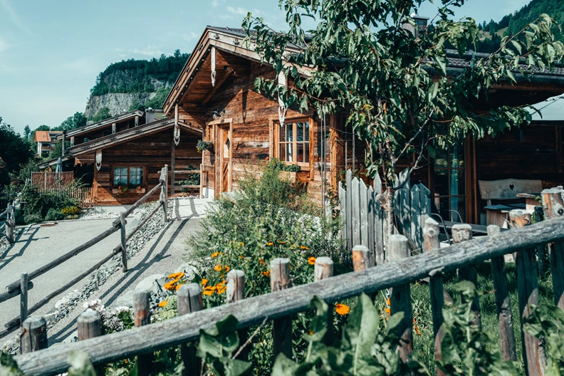 Chalet mit Holzzaun und B&auml;umen im Vordergrund