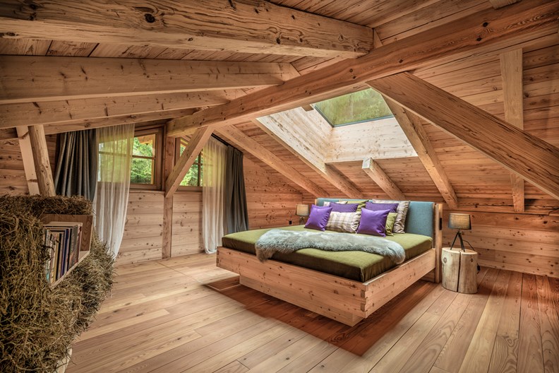 Schlafzimmer mit Panoramafenster und Holzdachstuhl