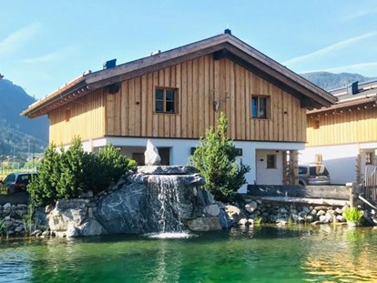 Hüttendorf - Schinking - Eines unserer Chalet Hütten mit unserem Naturschwimmteich davor.  - Sieglhub Chalets Appartements Hotel
