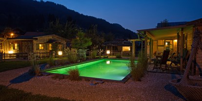 Hüttendorf - Pools: Schwimmteich - Grän - Garten am Abend
 - Dorf Chalet