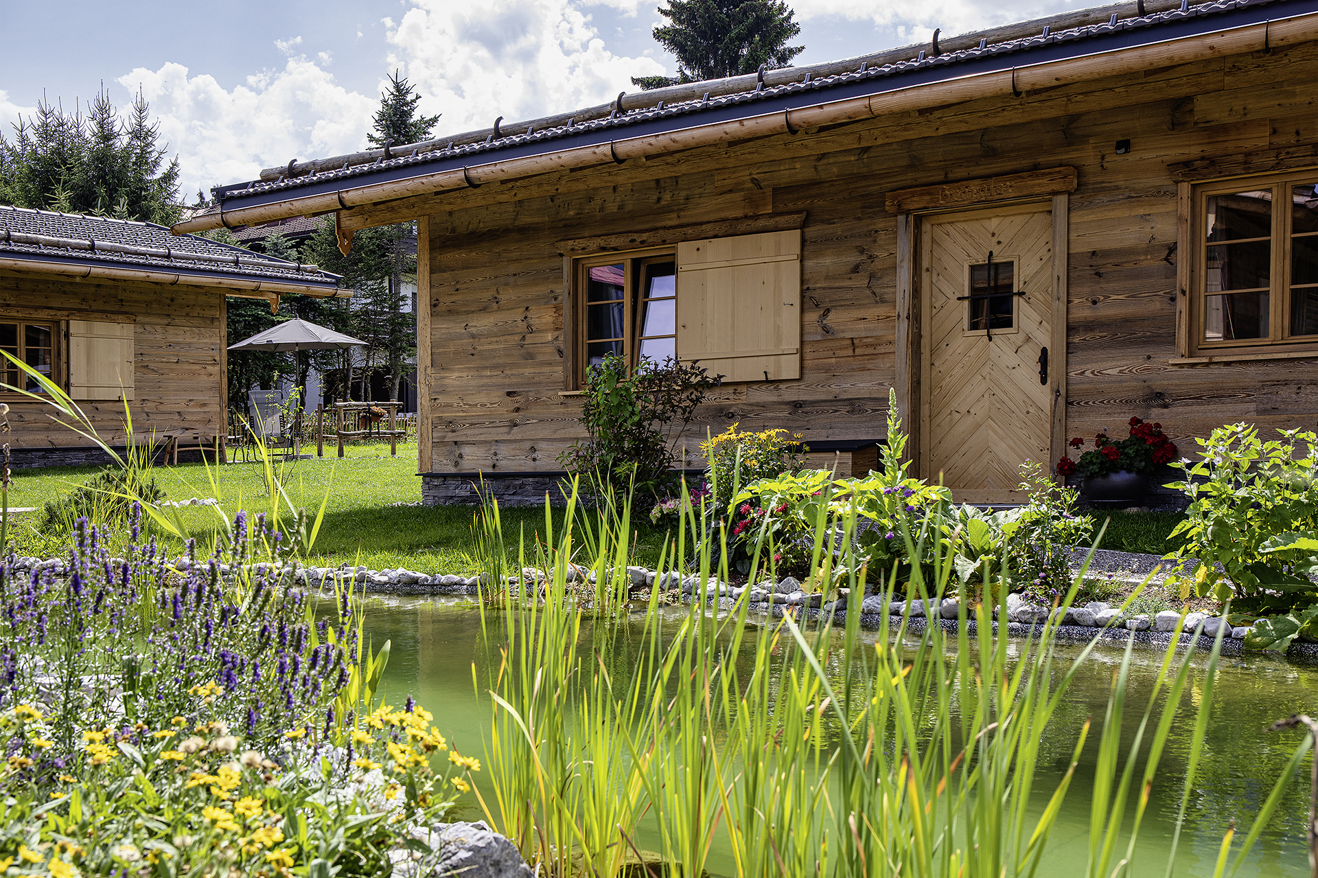 Chalet - Chalets mit Badeteich und Pflanzen im Vordergrund - Alpglück Chalets *****