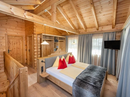 Hüttendorf - Doppelbett - Mandling - Eltern-Schlafzimmer mit offenem Schrank, Sat-TV und Zugang zum Balkon. - Dorf-Chalets Filzmoos