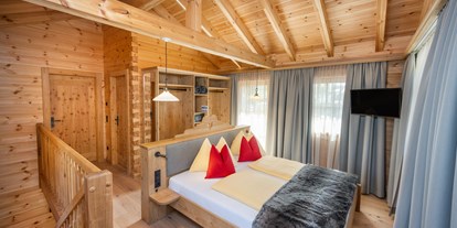 Hüttendorf - Schwerpunkt: Wanderurlaub - Großarl - Eltern-Schlafzimmer mit offenem Schrank, Sat-TV und Zugang zum Balkon. - Dorf-Chalets Filzmoos