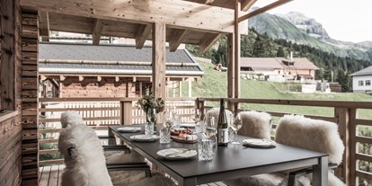 Hüttendorf - Typ: Lodge - PLZ 6532 (Österreich) - überdachter Außemsitzplatz mit Möbeln, Fellen, Laternen... - Aadla Walser-Chalets am Arlberg