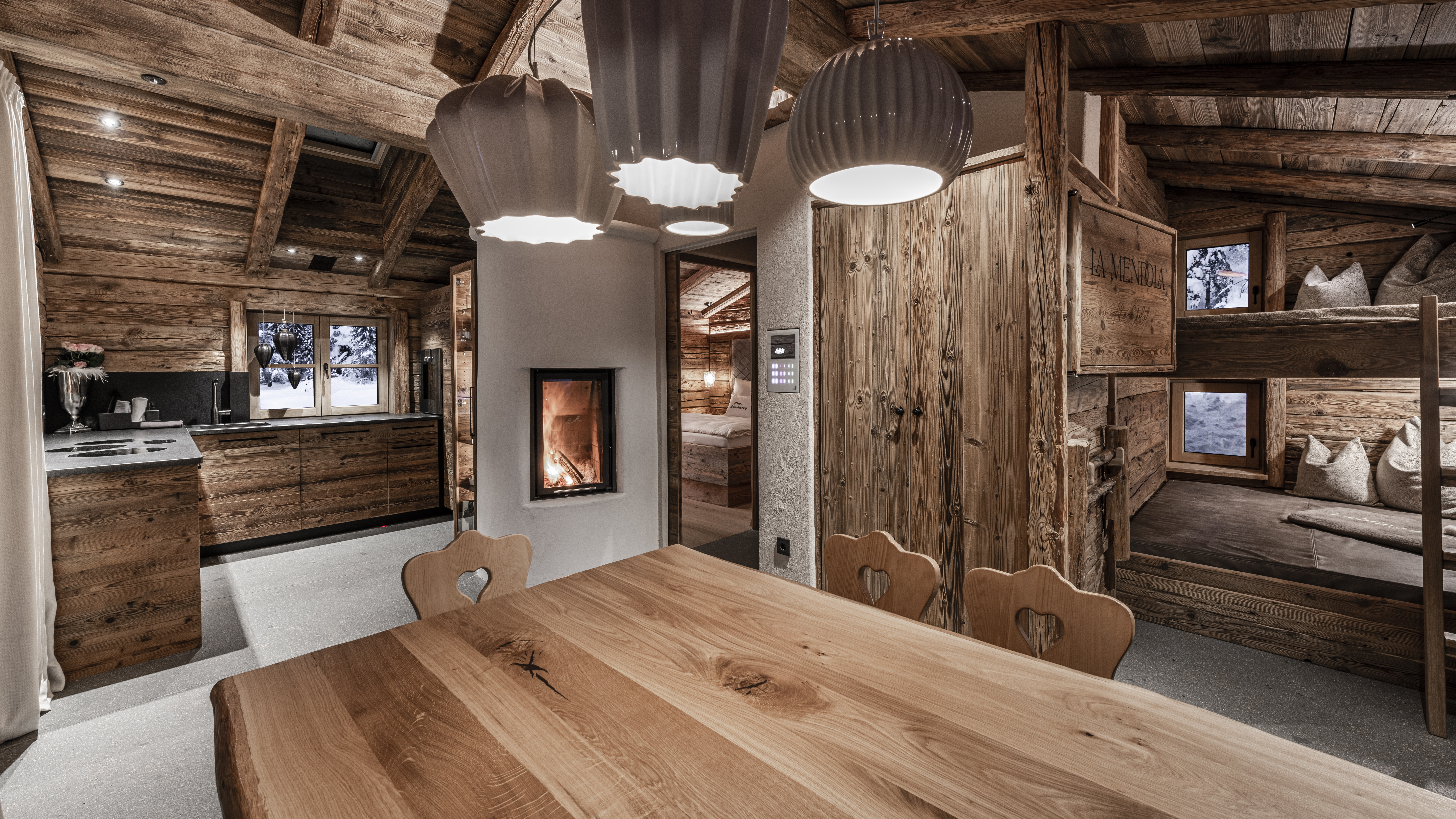 Chalet: Küche, Küchentisch und Rechts unser Stockbett mit TV im Wohn- und Essbereich im Erdgeschoss - La Mendola Alm-Chalet