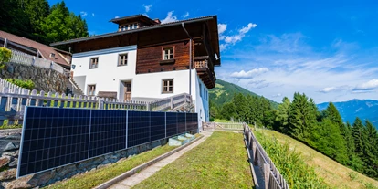 Hüttendorf - Chaletgröße: 8 - 10 Personen - Ferienhaus - Außenansicht mit PV-Anlage im Garten - Beim Rauter – Emberger Alm