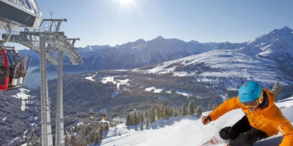 Hüttendorf - Chaletgröße: 4 - 6 Personen - Pinzgau - Wer Schnee sucht, ist in Hochkrimml an der richtigen Adresse. Der ganz auf Wintersportler zugeschnittene Ferienort bietet sonnige und beschneite Pistenabfahrten mit einer langen Saison von Anfang Dezember bis weit in den April. Der Ort selbst ist ruhiger als das benachbarte Königsleiten und damit ideal für Gäste, die Besinnlichkeit mögen. Gleichwohl gibt es hier Gelegenheiten zur abendlichen Entspannung. Kein Wunder, dass Hochkrimml immer beliebter wird. 
 Warum entscheidet man sich für die hochgelegenen Alpenorte? Weil sie dem Himmel näher sind und eine atemberaubende Aussicht bieten! Das Gefühl, aus dem Haus zu kommen, bereits auf den Brettern zu stehen und direkt ins Tal zu wedeln, ist einfach unvergleichlich – wobei „Tal“ vielleicht nicht der richtige Begriff ist, denn der niedrigste Punkt ist immer noch etwa 1400 Meter hoch gelegen. Auf der anderen Seite erobern Sie über Königsleiten die Weiten der Gerlosplatte. Aber auch in Hochkrimml finden Sie genügend Infrastruktur für den Skifahrer: neben modernen Liften haben Sie hier eine Skischule und ein Skigeschäft mit Skiverleih direkt im Dorf. Auch der Bus steht Ihnen zur Verfügung: Er verkehrt in alle nahegelegenen Skiorte: Neukirchen, Wald, Krimml und Königsleiten.
Wenn Sie weniger Adrenalin beim Sport brauchen, können Sie von hier aus herrliche, liebevoll vorbereitete Langlaufloipen nutzen. Auch eine Rodelabfahrt steht Ihnen zur Verfügung. Oder ist Ihnen eher nach einer zünftigen Winterwanderung zumute? Dann empfehlen wir Ihnen eine Schneeschuhwanderung, zum Beispiel an die Krimmler Wasserfälle, die auch im Winter sehr beeindruckend sind. Über 300 Meter stürzt das Wasser hier den Fels hinab. - Sam-Alm