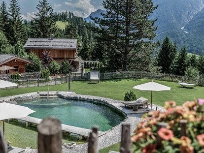 Hüttendorf - Schröcken - Ein idyllischer Naturbadesee mitten im Benglerwald Berg Chaletdorf lädt im Sommer zum erfrischenden Schwimmen und Entspannen in traumhafter Bergkulisse ein. - Benglerwald Berg Chaletdorf