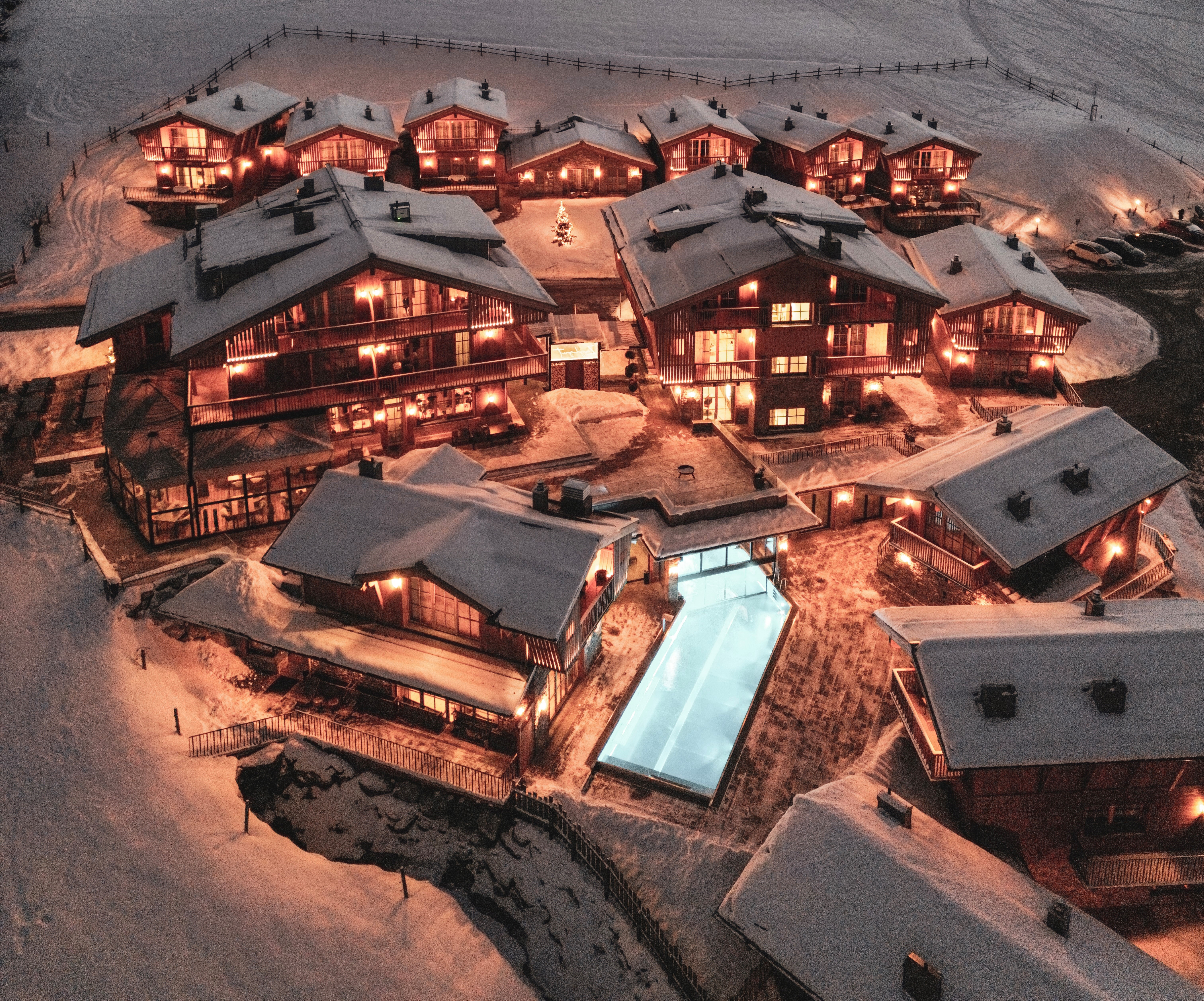Hüttendorf - Ellmau - Ein besonderer Blick auf das Zaglgut bei Nacht: Die stimmungsvoll beleuchteten Chalets erstrahlen inmitten der verschneiten Winterlandschaft und schaffen eine einzigartige Atmosphäre vor der beeindruckenden Bergkulisse. - Bergdorf Hotel Zaglgut Ski In & Ski Out