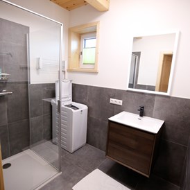 Chalet: Badezimmer mit Dusche und Waschmaschine im Erdgeschoss - Designchalets Heidialm-Falkertsee