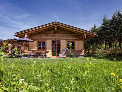 Hüttendorf - Schröcken - Außenansicht Chalet Sennar mit grüner Blumenwiese im Vordergrund - Alpglück Chalets *****
