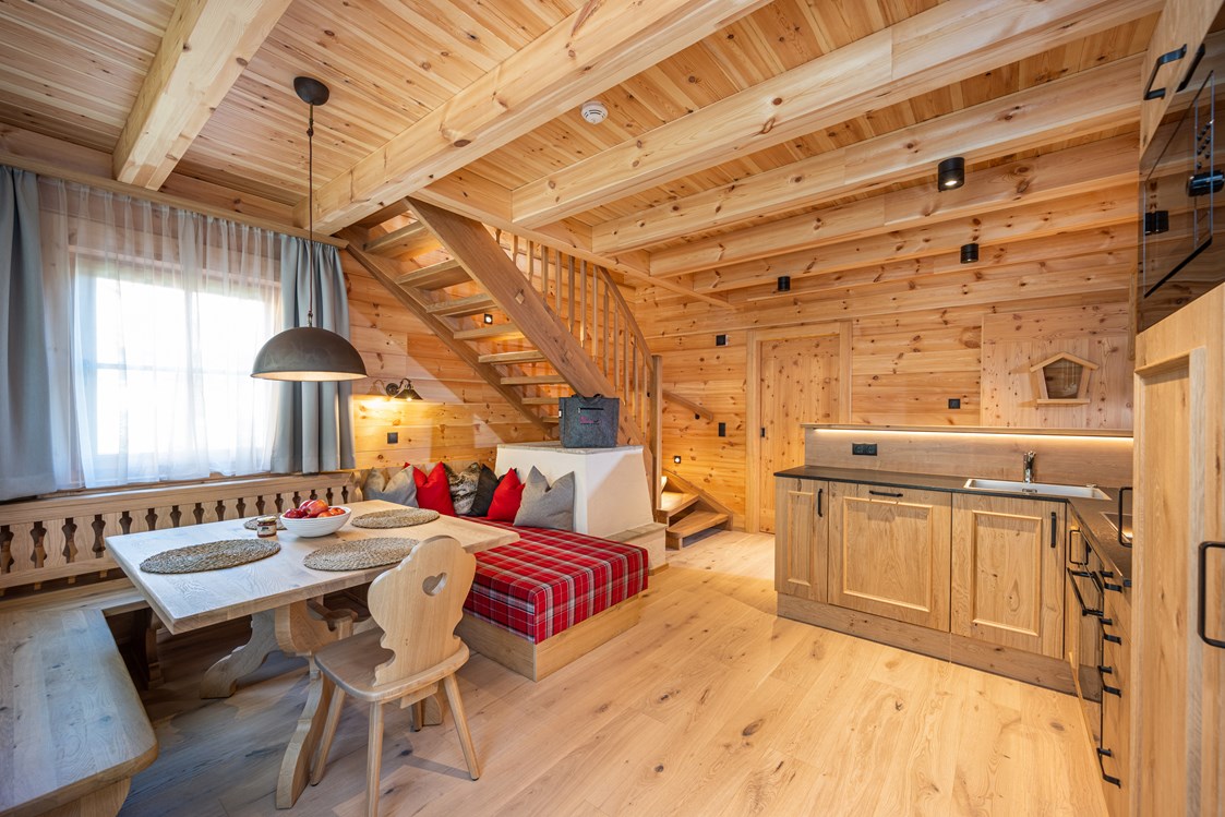 Chalet: Wohn / Essbereich mit Elektroofen und Küchenzeile.
Treppe nach oben zu den Schlafzimmern. - Dorf-Chalets Filzmoos