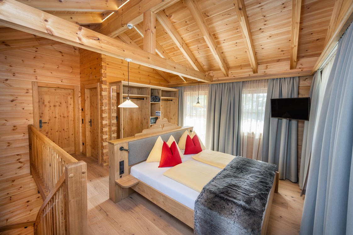 Chalet: Eltern-Schlafzimmer mit offenem Schrank, Sat-TV und Zugang zum Balkon. - Dorf-Chalets Filzmoos