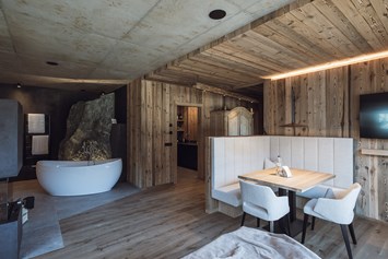 Chalet: Freistehende Badewanne, Kamin und Essbereich im Landschaftschalet
Im Hintergrund die Steinfelsendusche und die Küche - Amus Chalets Dolomites