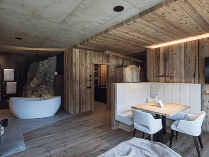 Hüttendorf - Hot Tub: beim Chalet - Freistehende Badewanne, Kamin und Essbereich im Landschafts-Chalet
Im Hintergrund die Steinfelsendusche und die Küche - Amus Chalets Dolomites