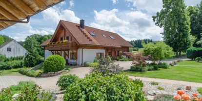 Hüttendorf - Parkplatz direkt an der Hütte - Außenansicht des Blockhäuserls mit Garten - Heumanns Blockhäuser am Wald