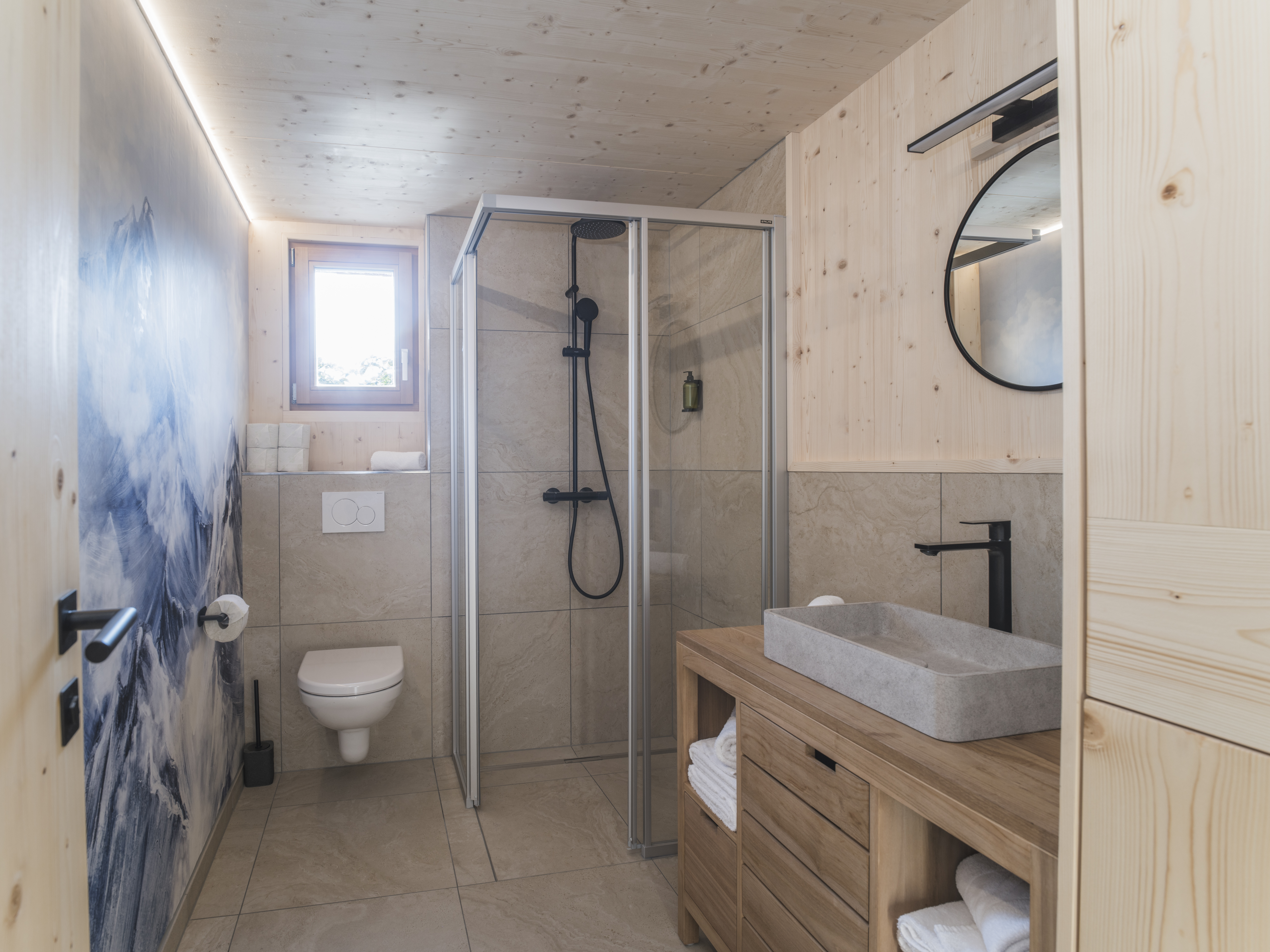 Chalet: Modernes Bad im Tiny Chalet Kalipé mit Dusche, WC und Waschbecken – ausgestattet mit Pflegeartikeln und frischen Handtüchern. - ALPEGG CHALETS