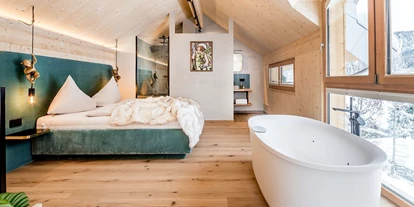 Hüttendorf - Weng (Goldegg) - Casa Defrancesco: Kuscheliges Doppelbett und Swirlpool mit Blick auf die Steinplatte, im Hintergrund modernes Badezimmer – perfekt für Entspannung und Komfort. - ALPEGG CHALETS