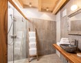 Chalet: Badezimmer mit Steinwaschbecken und Regendusche - ALPEGG CHALETS